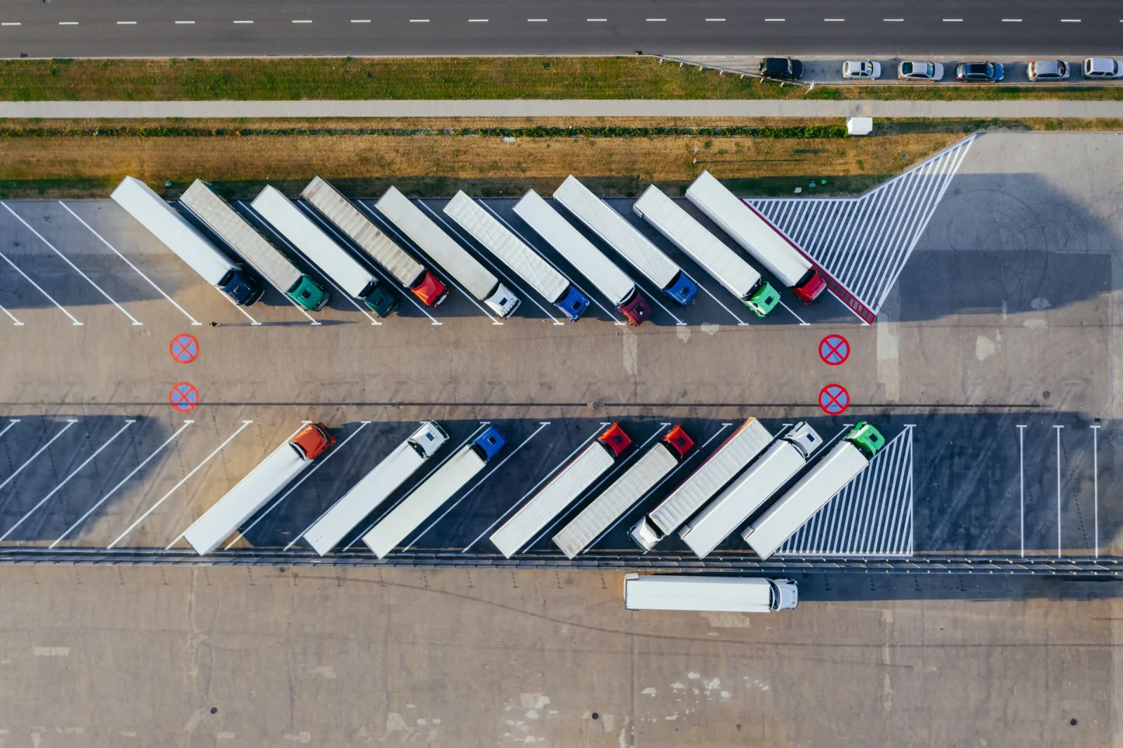 Aerial view of semi-trailer trucks parked in angled rows at a freight lot