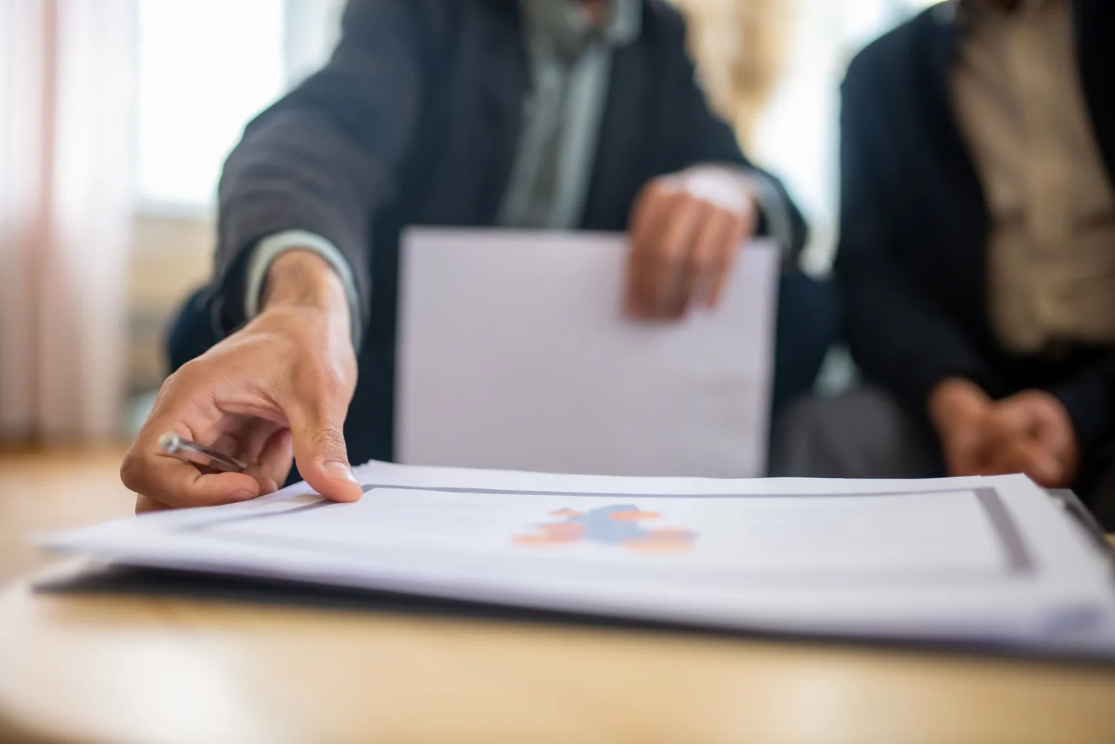 Close-up of a businessman reaching for documents on an office desk
