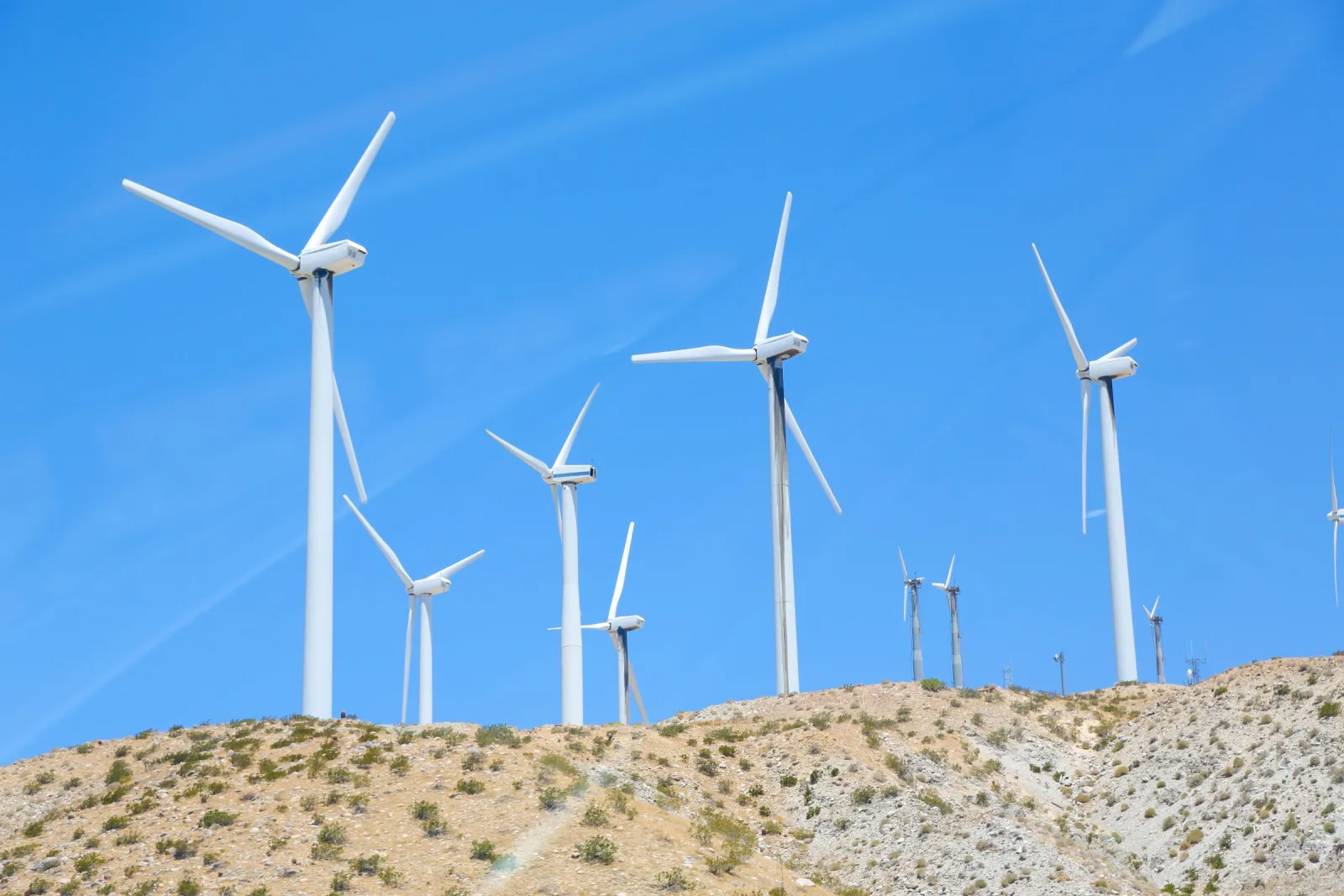 A row of wind turbines on a sunny day in a rural landscape